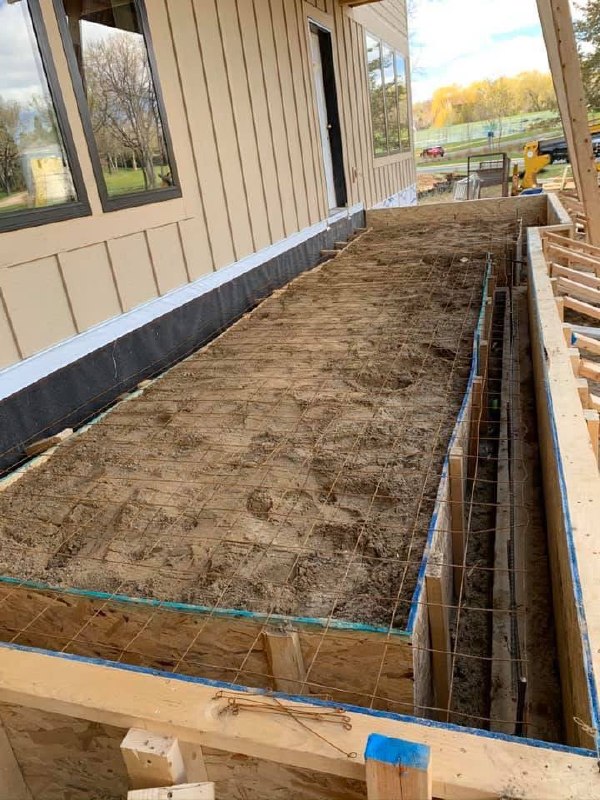 Prepared exterior slab area with forms and reinforcement beside a building