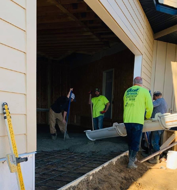 Crew placing concrete at the open side of a framed building