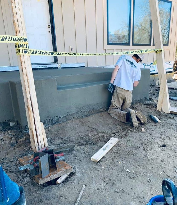 Worker finishing a concrete edge beside a building