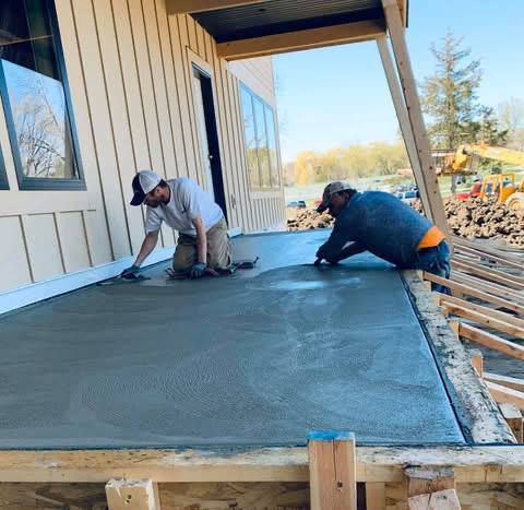 Crew hand-finishing a freshly placed exterior concrete slab