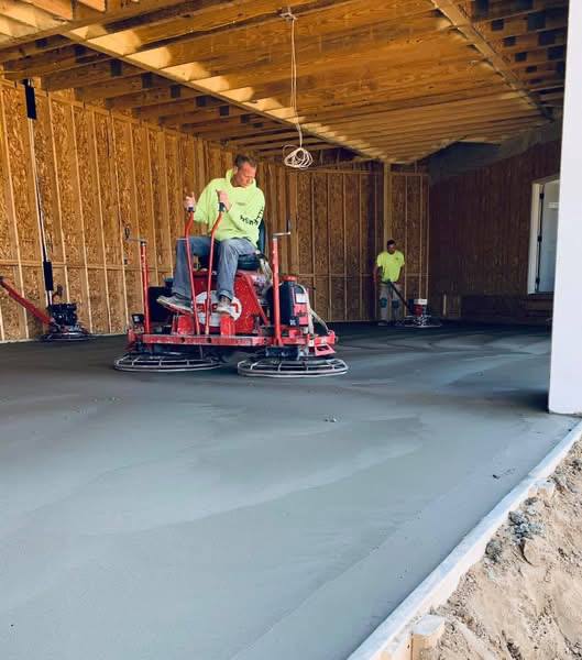 Worker operating a power trowel on an interior concrete slab